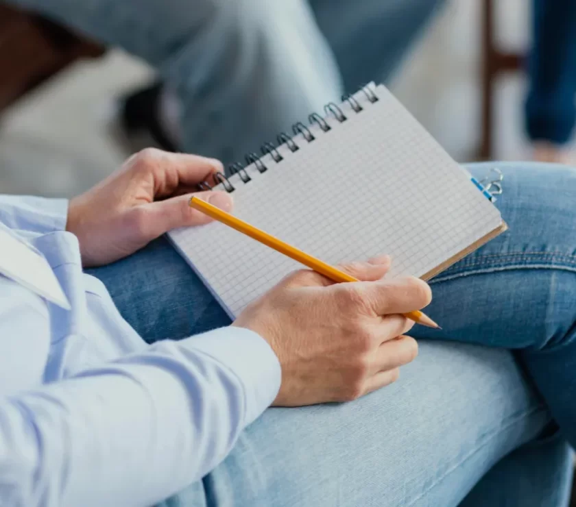 Therapist writing notes on a notepad during a session