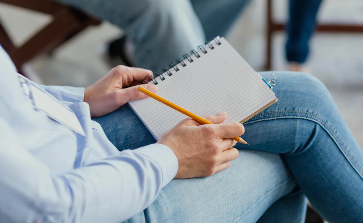 Therapist writing notes on a notepad during a session